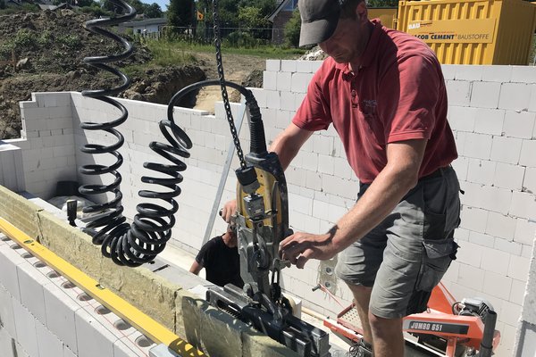 Handwerker bedient eine Maschine zur Bearbeitung von Baustellenmaterialien auf einer Baustelle.