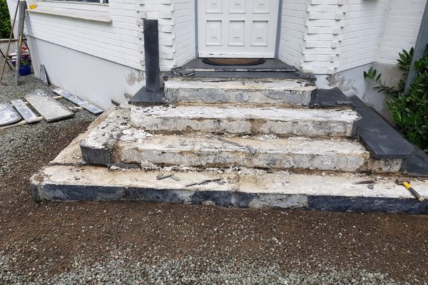 Abgebaute Treppe mit unvollständigen Stufen und freiliegendem Untergrund vor einem Eingang.