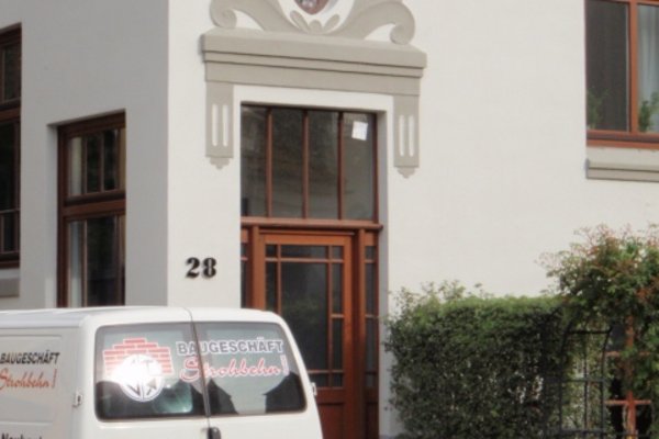 Eingang eines Hauses mit dekorativem Oberlicht und einem Lieferwagen des Bauunternehmens in der Nähe.
