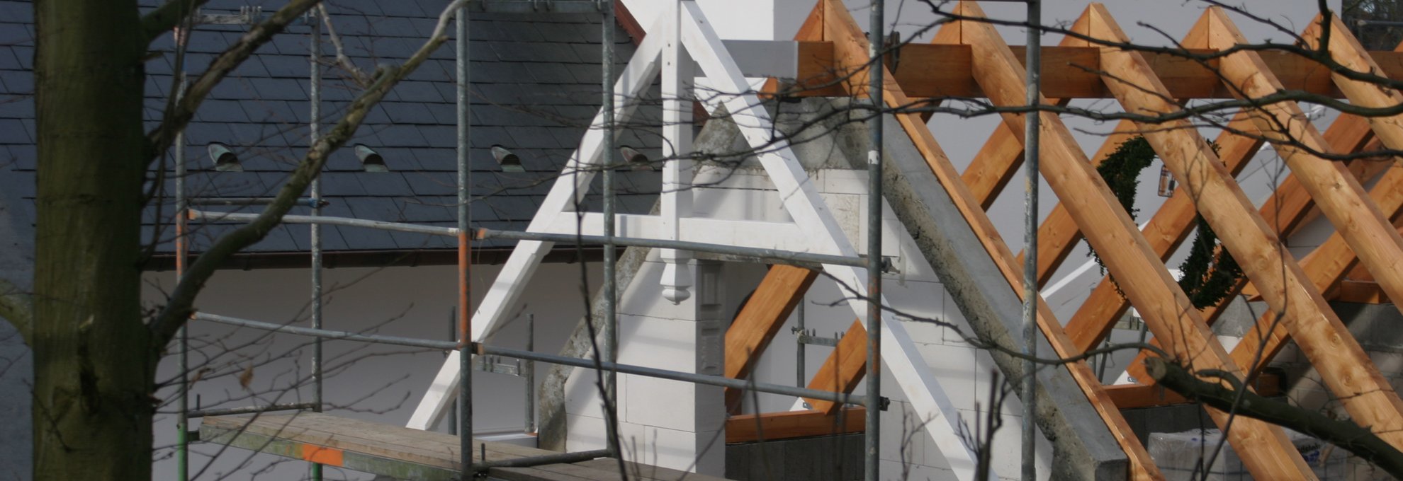 Sanierungsarbeiten an einem Dach mit Holzsparren und Gerüstkonstruktion.
