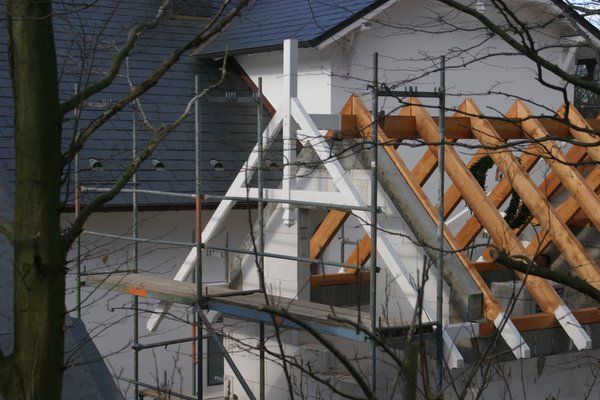 Sanierungsarbeiten an einem Dach mit Holzsparren und Gerüstkonstruktion.