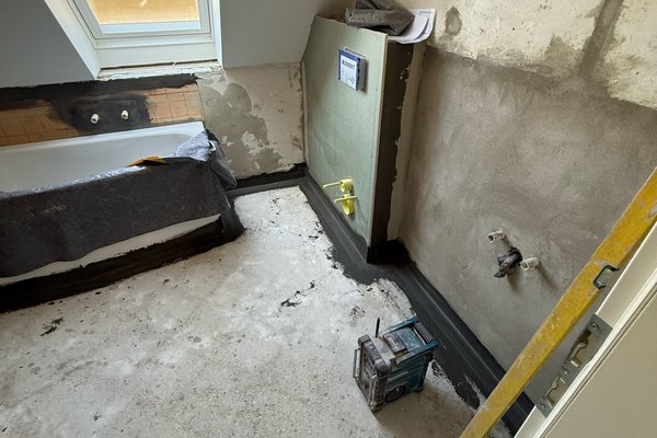 Sanierungsarbeiten in einem Badezimmer mit freiliegenden Wänden und unvollständigem Bodenbelag.