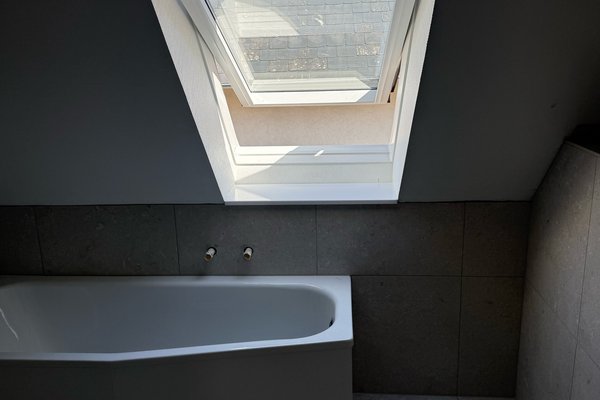 Moderne Badgestaltung mit freistehender Badewanne und Dachfenster, das Tageslicht hereinlässt.